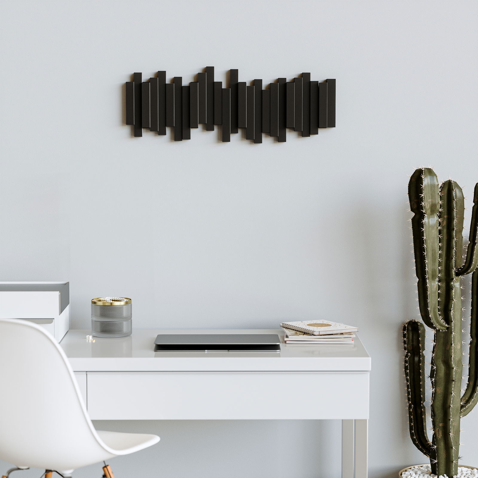 Moderne Wandgarderobe in Schwarz mit geometrischem Design, an einer hellen Wand über einem Schreibtisch montiert, seitliche Perspektive.