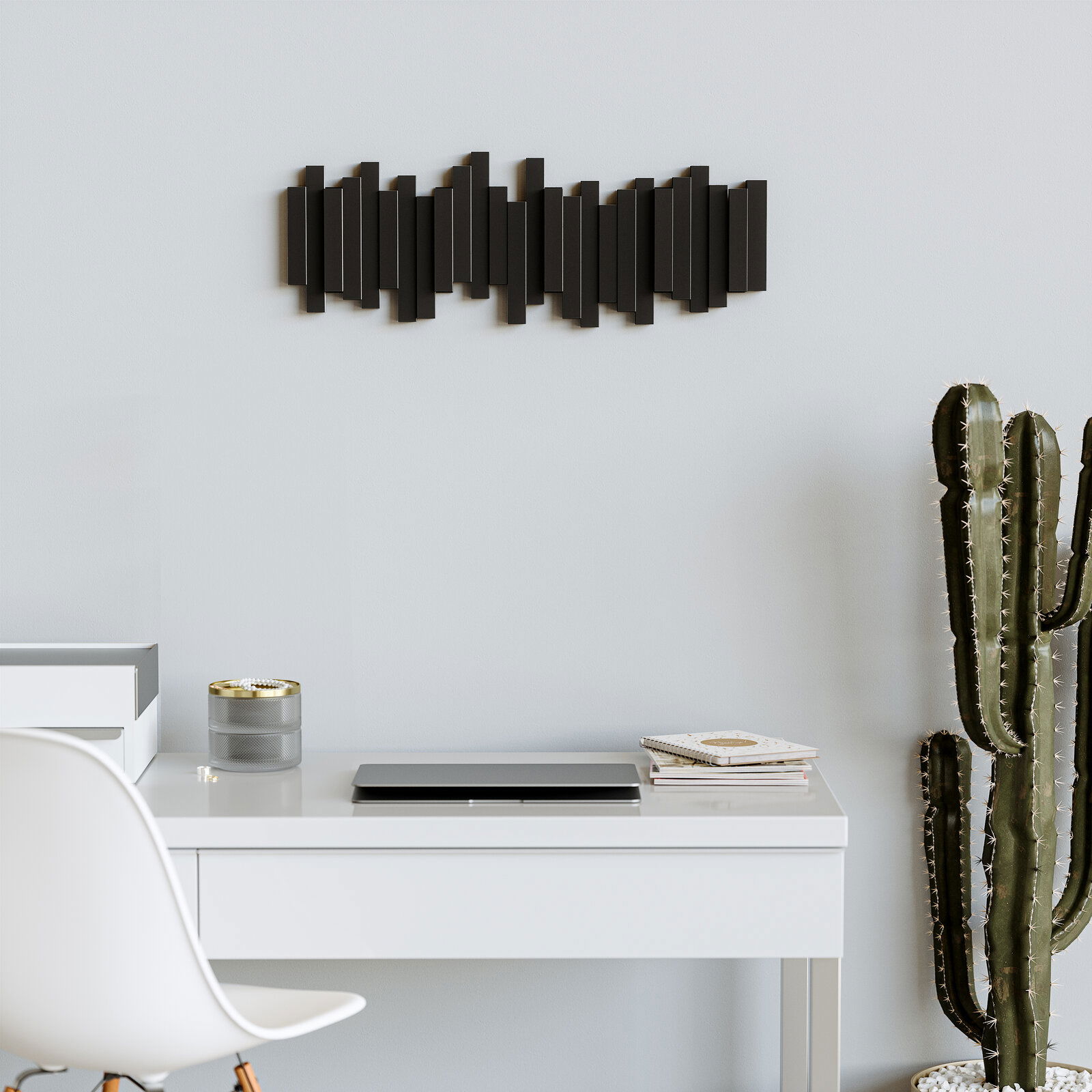Moderne Wandgarderobe in Schwarz mit geometrischem Design, an einer hellen Wand über einem Schreibtisch montiert, seitliche Perspektive.