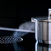 WMF Topf aus Cromargan Edelstahl mit Deckel, seitliche Perspektive, auf einem Herd mit Dampf.