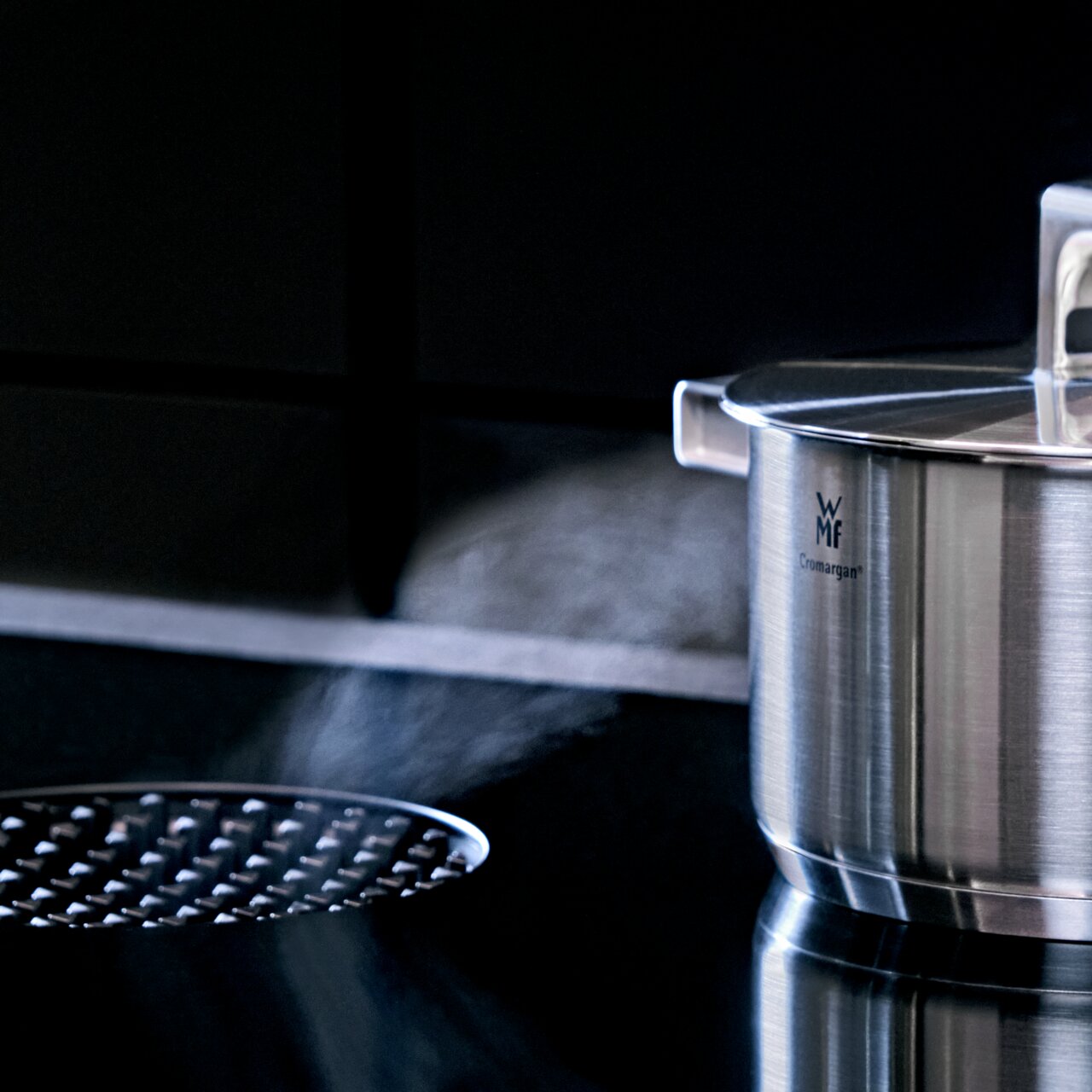 WMF Topf aus Cromargan Edelstahl mit Deckel, seitliche Perspektive, auf einem Herd mit Dampf.
