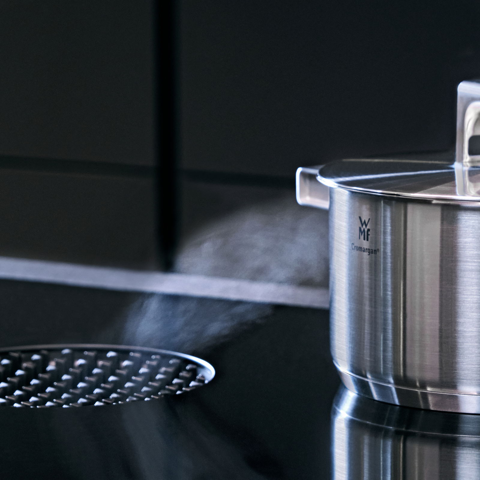 WMF Topf aus Cromargan Edelstahl mit Deckel, seitliche Perspektive, auf einem Herd mit Dampf.