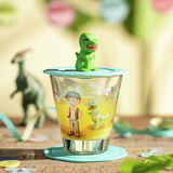 Trinkglas mit Dinosaurier-Motiv und grünem Dinosaurier-Deckel, seitliche Perspektive