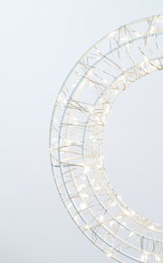 Nahaufnahme eines LED-Kranzes mit einem Durchmesser von 30 cm, umwickelt mit leuchtenden Lichterketten, seitliche Perspektive.