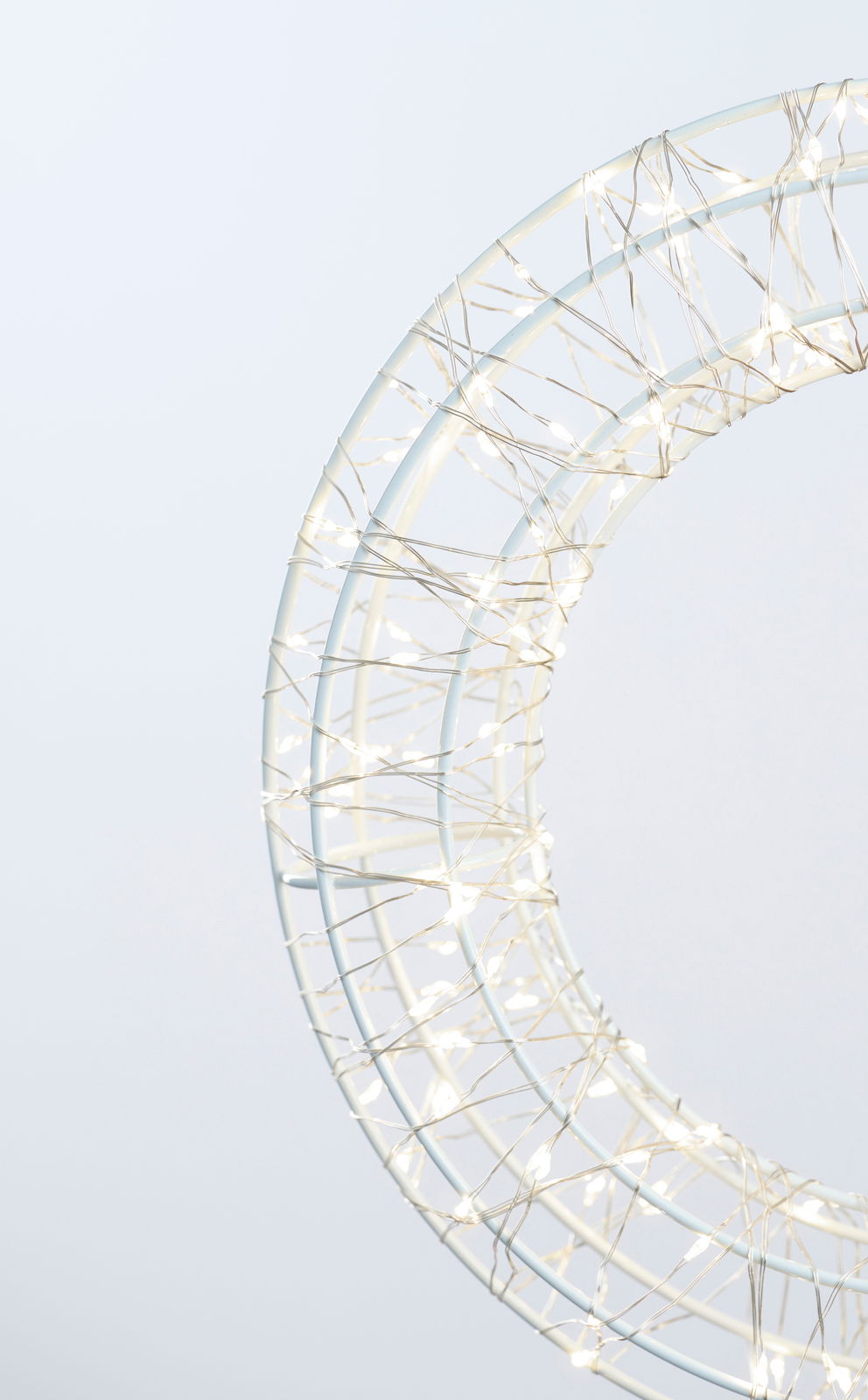 Nahaufnahme eines LED-Kranzes mit einem Durchmesser von 30 cm, umwickelt mit leuchtenden Lichterketten, seitliche Perspektive.