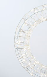 Nahaufnahme eines LED-Kranzes mit einem Durchmesser von 30 cm, umwickelt mit leuchtenden Lichterketten, seitliche Perspektive.