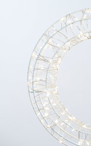 Nahaufnahme eines LED-Kranzes mit einem Durchmesser von 30 cm, umwickelt mit leuchtenden Lichterketten, seitliche Perspektive.