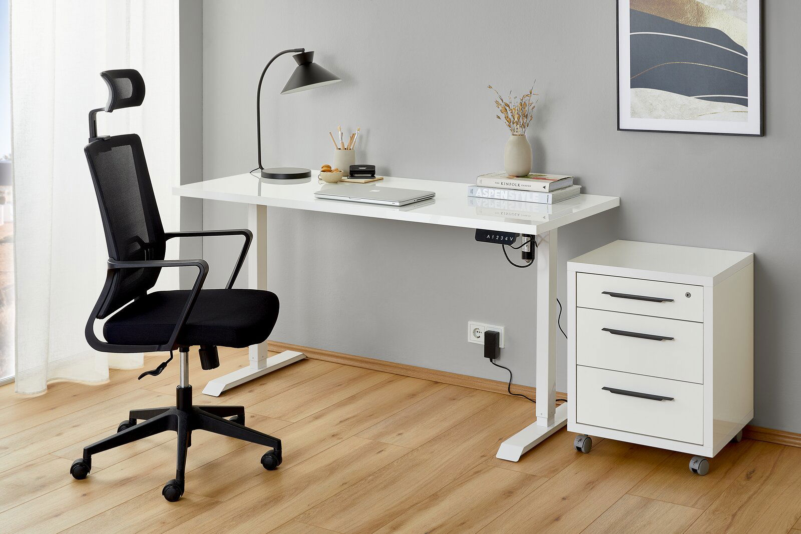 Moderner Arbeitsplatz mit elektrischem Fußgestell, weißem Schreibtisch, ergonomischem Bürostuhl und Rollcontainer, seitliche Perspektive.