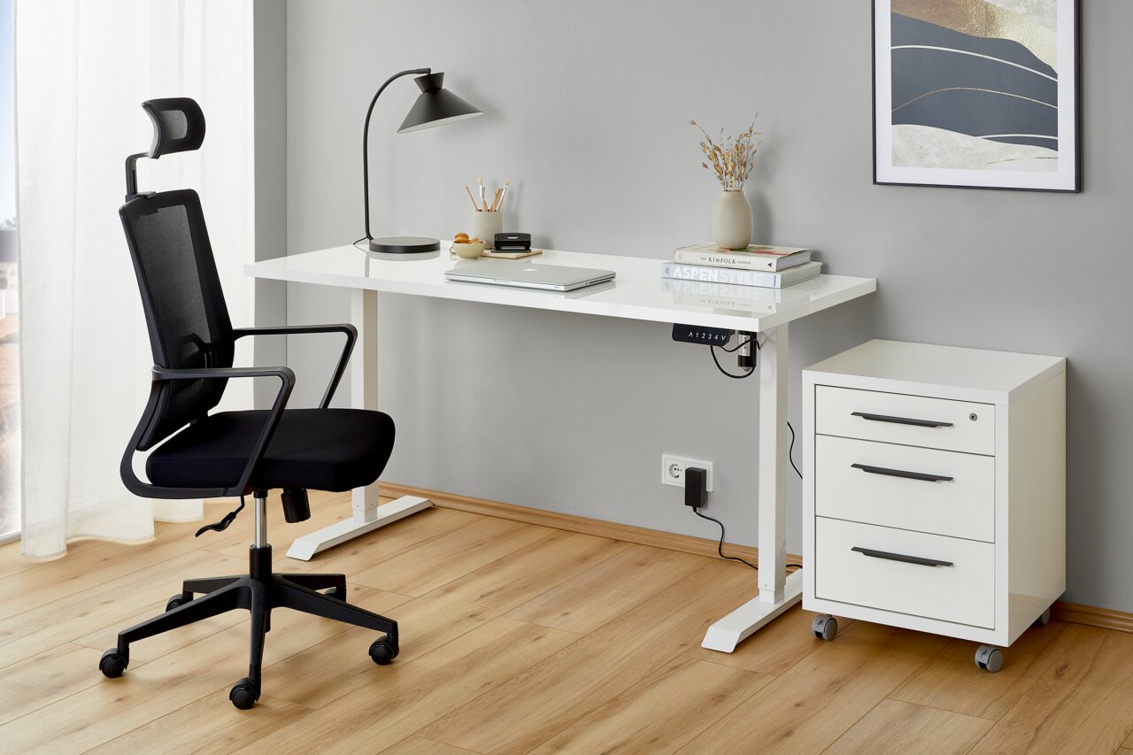 Moderner Arbeitsplatz mit elektrischem Fußgestell, weißem Schreibtisch, ergonomischem Bürostuhl und Rollcontainer, seitliche Perspektive.