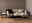 Moderner Couchtisch mit hellem Holz und schwarzem Metallgestell, frontal vor einem beigen Sofa in einem stilvoll eingerichteten Wohnzimmer.
