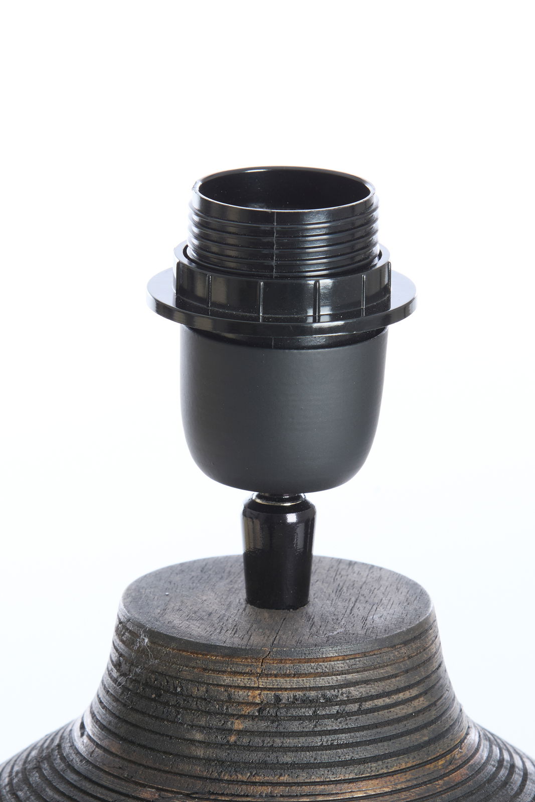 Nahaufnahme eines Lampenfußes mit schwarzer Fassung auf einem strukturierten, hölzernen Sockel, seitliche Perspektive.