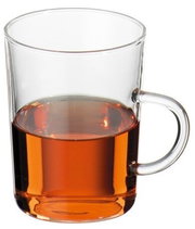Transparente Glastasse mit Henkel, teilweise mit bernsteinfarbenem Tee gefüllt, freigestellt auf weißem Hintergrund, Frontansicht leicht von oben