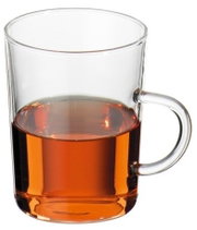 Doorzichtige glazen kop met oor, gedeeltelijk gevuld met amberkleurige thee, vrijstaand op een witte achtergrond, vooraanzicht licht van bovenaf