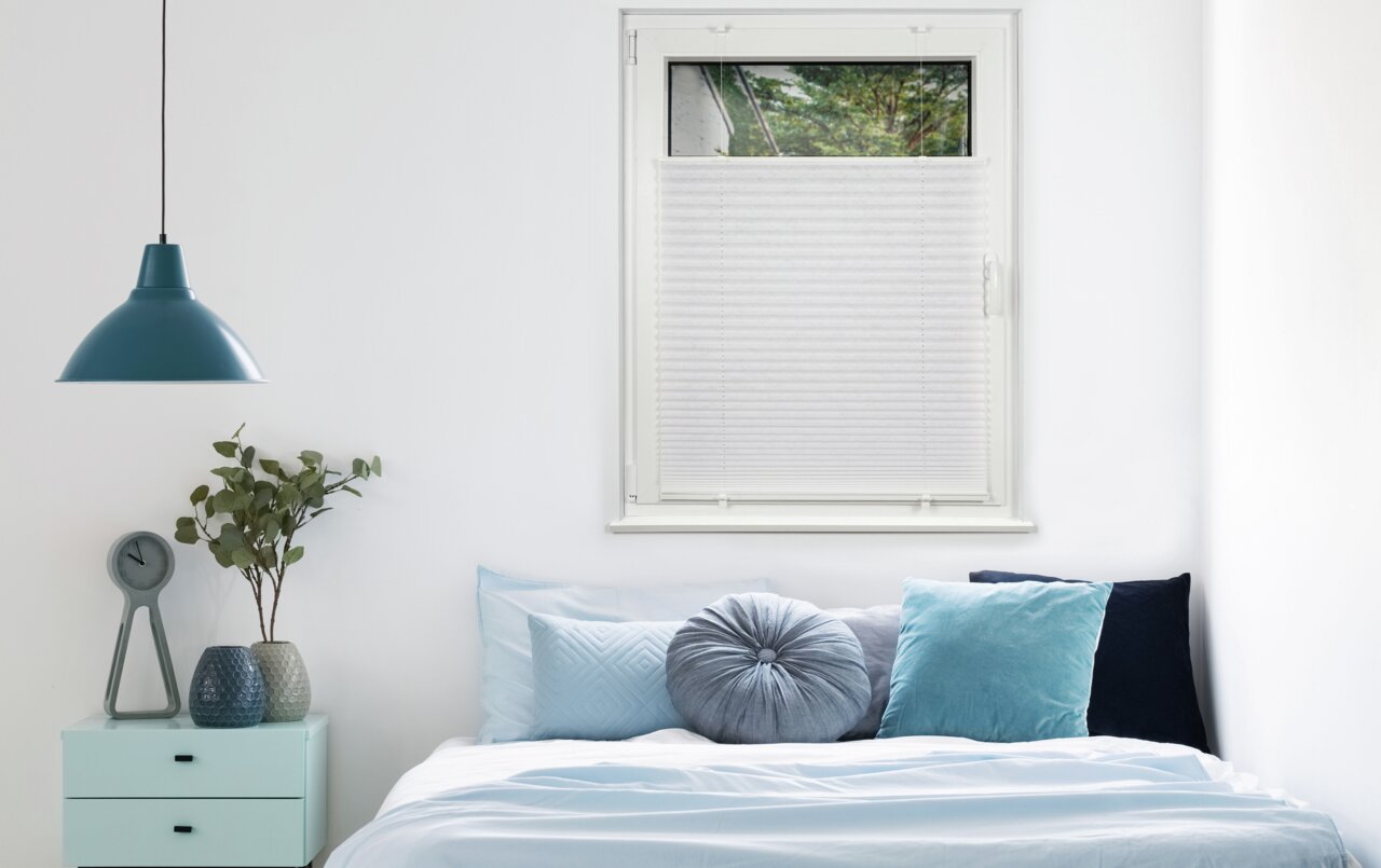 Plissee am Fenster in einem Schlafzimmer, seitliche Perspektive