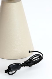 Nahaufnahme einer Tischleuchte mit konischem, cremefarbenem Schirm und schwarzem Kabel mit Schalter, seitliche Perspektive.