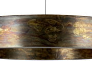 Close-up van een LED-hanglamp met een kunstzinnig gedessineerde, metalen kap in warme aardetinten, gezien vanuit de zijkant.