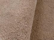 Nahaufnahme eines weichen, beigen Teppichs mit flauschiger Textur, seitliche Perspektive