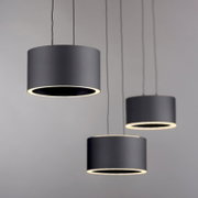 Drei moderne, zylindrische LED-Pendelleuchten in Schwarz, von unten betrachtet, mit warmem Lichtschein.