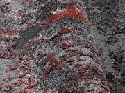 Nahaufnahme eines strukturierten Teppichs in Grau- und Rottönen, perspektivisch von der Seite aufgenommen.