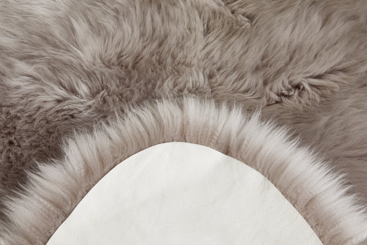 Nahaufnahme eines weichen, grauen Schaffells mit sichtbarer Rückseite, von oben betrachtet.