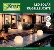 Solar Kugelleuchte 30cm im Garten bei Nacht, leuchtend auf einer Terrasse mit moderner Architektur im Hintergrund, seitliche Perspektive