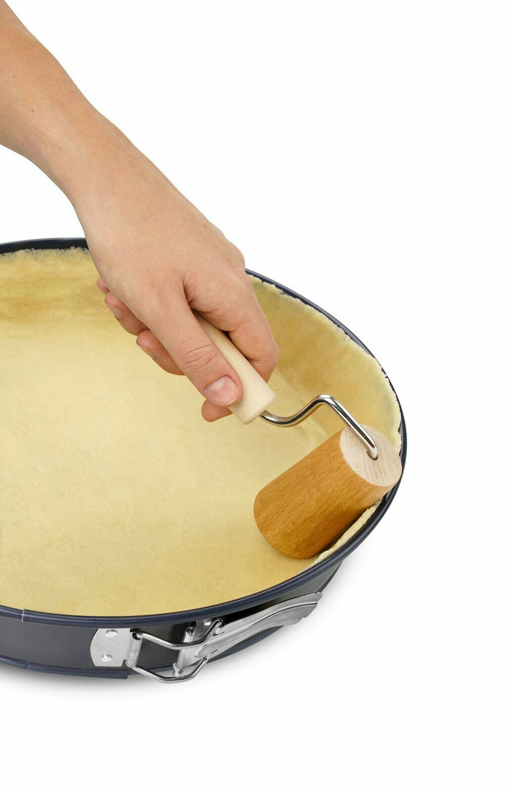Dr. Oetker Holzteigroller Hand hält einen kleinen Holzteigroller und rollt Teig in einer runden Backform aus, Ansicht von oben.