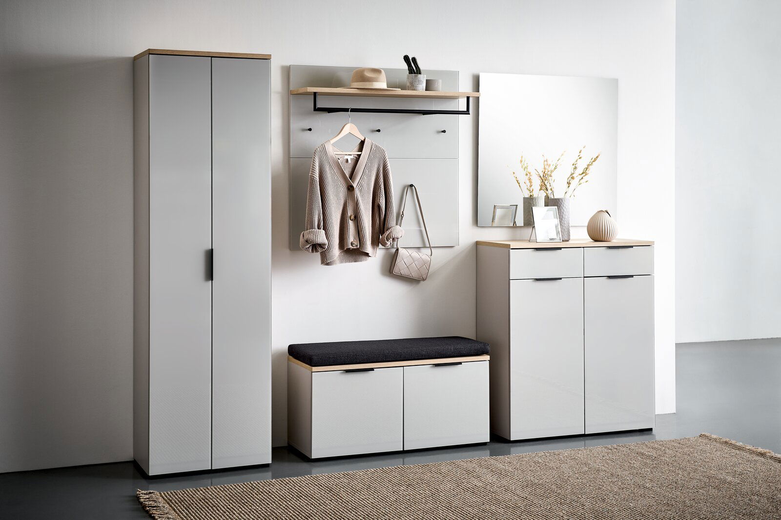 Voleo Schuhschrank NEW YORK Moderne Garderobenkombination in hellem Raum, bestehend aus einem hohen Schrank, einem Garderobenpaneel mit Haken und Ablage, einer Schuhbank mit Sitzkissen und einem Schuhschrank mit Spiegel. Frontalansicht.