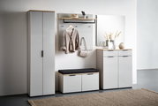 Moderne Garderobenkombination in hellem Raum, bestehend aus einem hohen Schrank, einem Garderobenpaneel mit Haken und Ablage, einer Schuhbank mit Sitzkissen und einem Schuhschrank mit Spiegel. Frontalansicht.