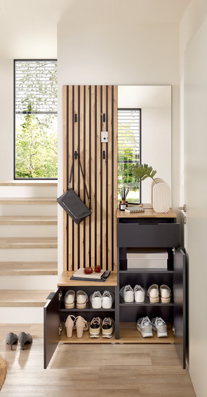 Compacte kapstok met houten en zwarte elementen, schoenenrek, spiegel en opbergvlak, gefotografeerd vanaf de voorkant.