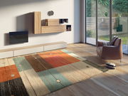 Moderner Frisé-Teppich in einem Wohnzimmer mit geometrischem Muster in warmen Farben, aus der Perspektive von schräg oben fotografiert.