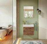Modernes Gästebad mit hängendem Waschtisch aus Holz, grüne Wand, beleuchteter Spiegel und dekorative Hängelampen, seitliche Perspektive.
