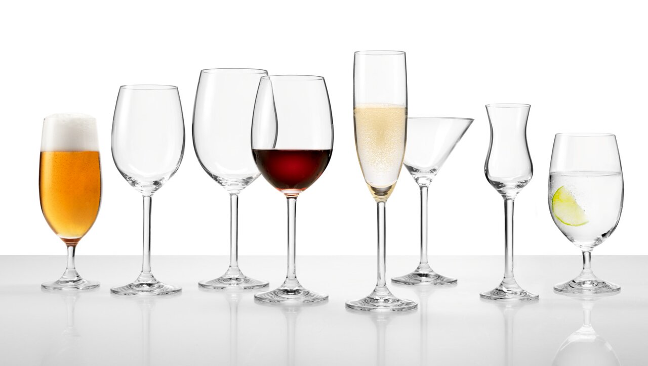 Eine Reihe von verschiedenen Gläsern, darunter ein Sektglas mit Sekt, aus seitlicher Perspektive fotografiert.