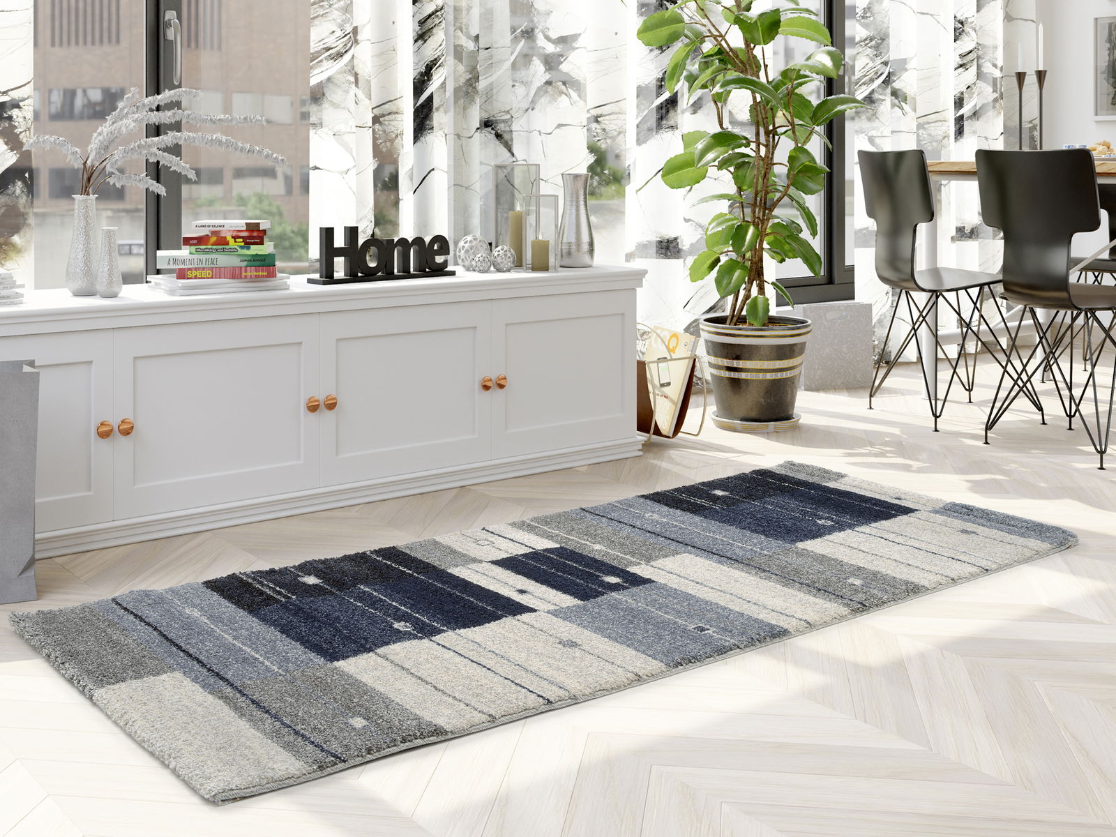 Moderner Frisé-Teppich in Grautönen mit geometrischem Muster, in einem hellen Wohnzimmer mit großen Fenstern und Pflanzen, aus seitlicher Perspektive fotografiert.