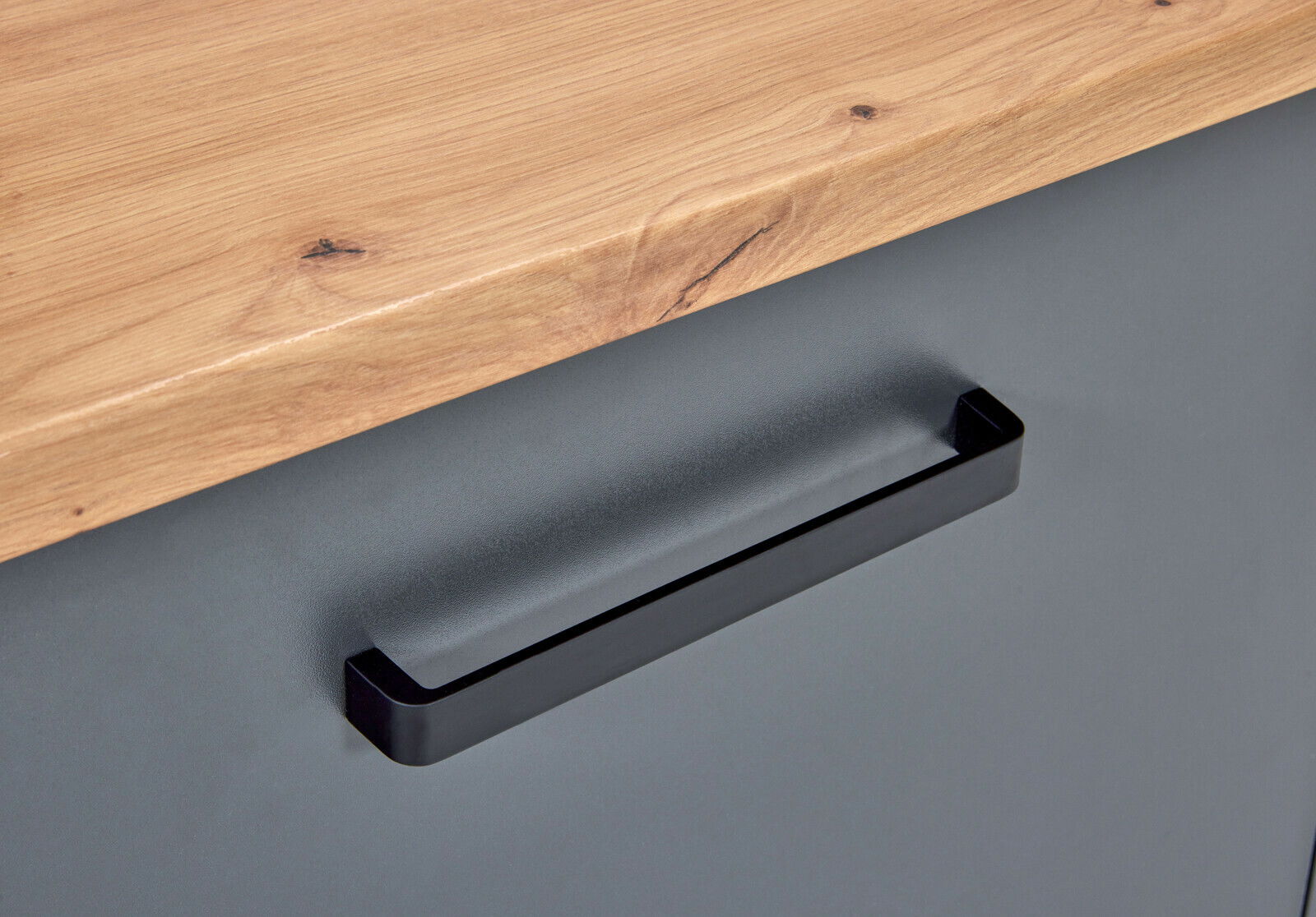 Nahaufnahme eines Spülenunterschranks mit Holzarbeitsplatte und schwarzem Griff, von oben betrachtet.