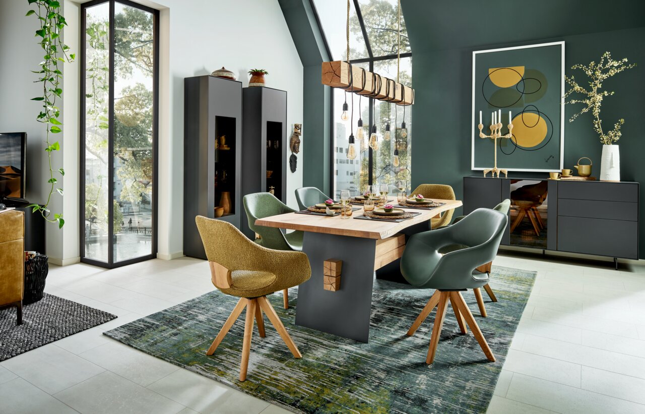 Moderne houten balkenlamp met hangende gloeilampen boven een eettafel in een stijlvol ingerichte eetkamer, gezien vanuit de zijkant.