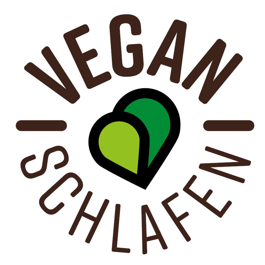 Logo mit der Aufschrift 'Vegan Schlafen' und zwei ineinander verschlungenen Herzen in Grün, aus der Vogelperspektive.