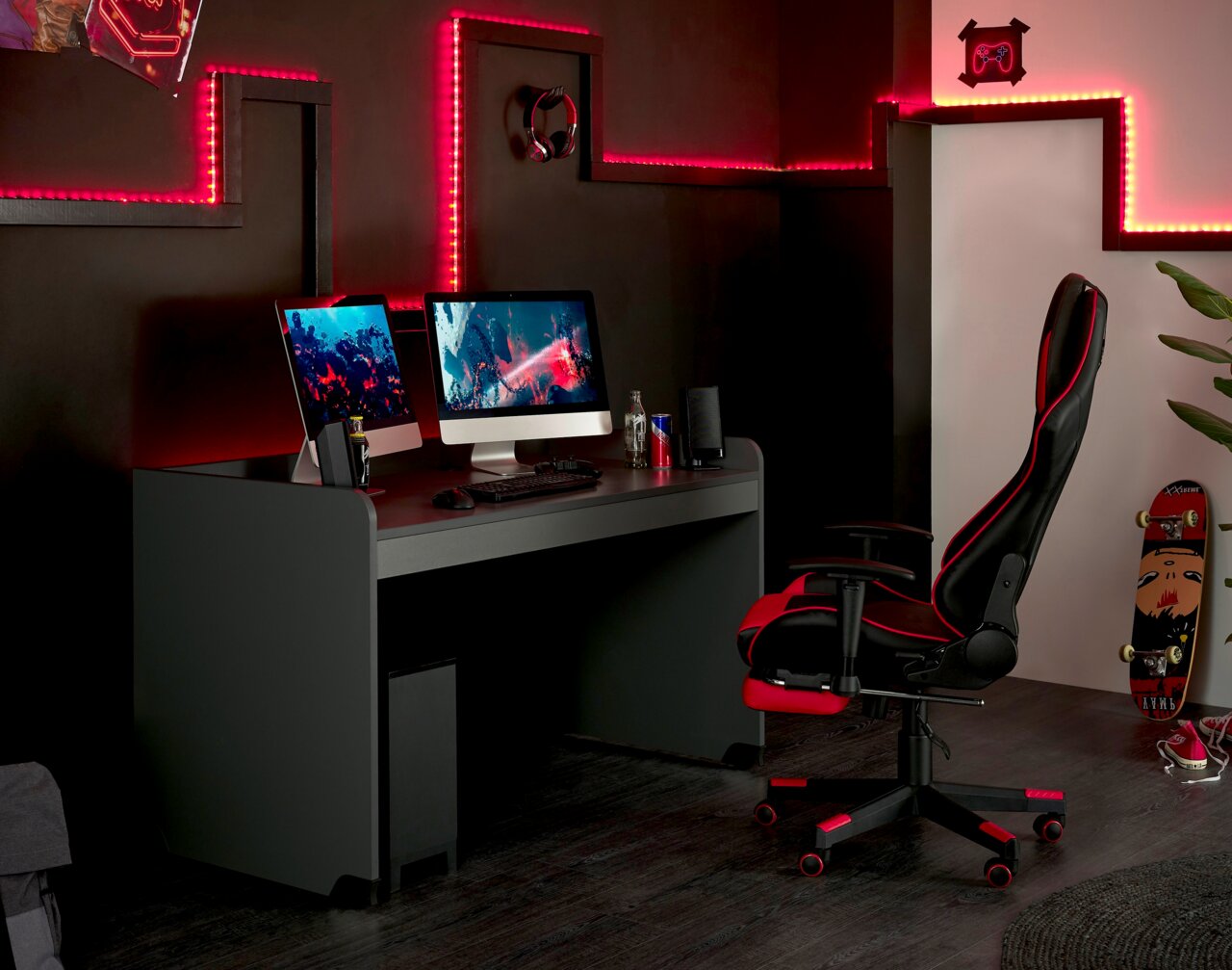 Moderner Schreibtisch in einem Gaming-Setup mit zwei Monitoren, umgeben von roten LED-Lichtern, seitliche Perspektive.