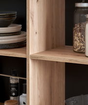 Nahaufnahme eines Holzregals mit Geschirr und Vorratsgläsern, seitliche Perspektive.