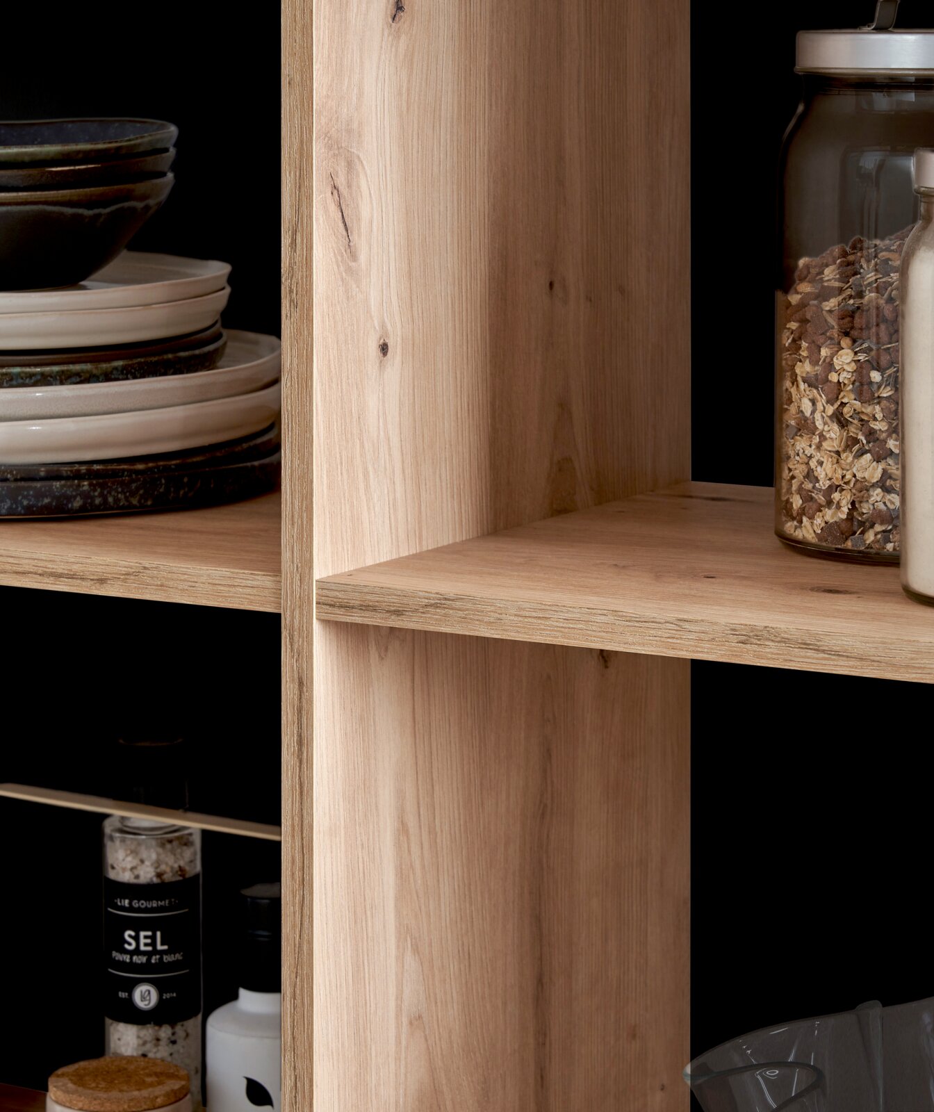 Close-up van een houten plank met serviesgoed en voorraadpotten, gezien vanaf de zijkant.