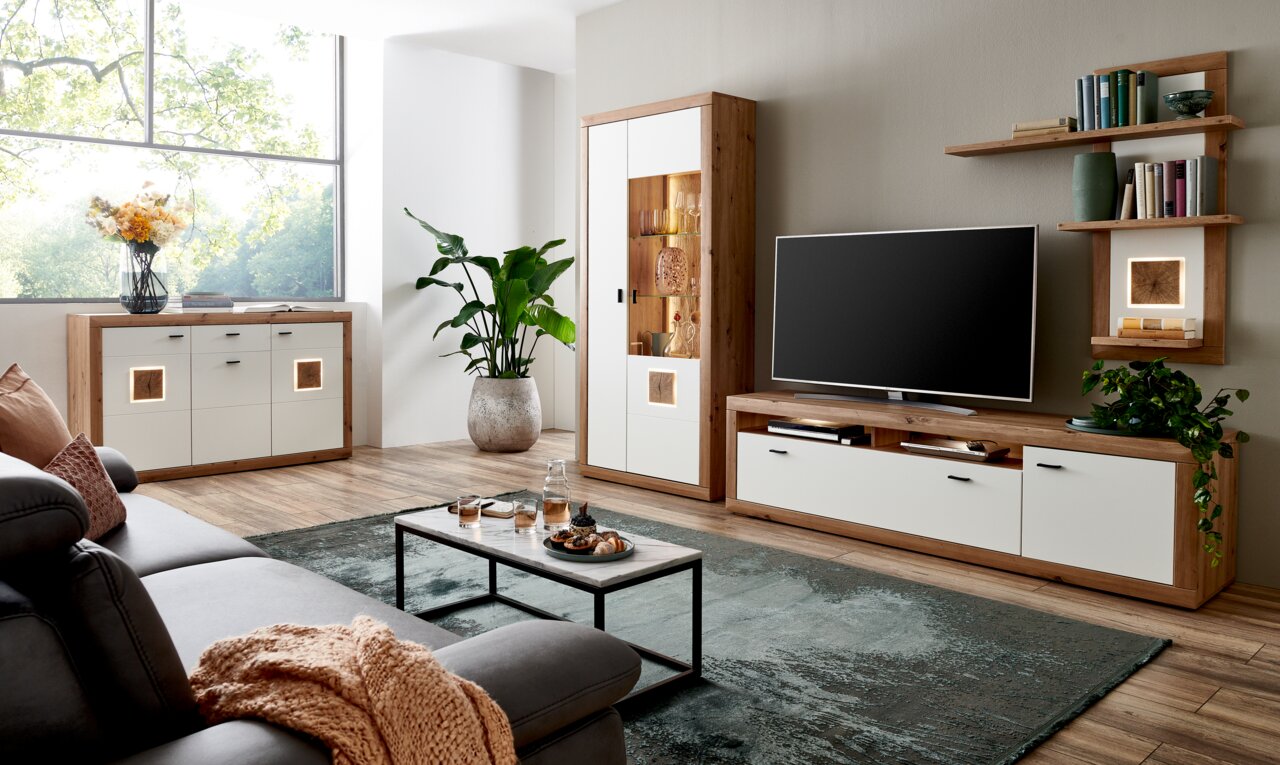 Moderne woonkamerinrichting met houten en witte accenten, bestaande uit een dressoir, een vitrinekast en een tv-meubel, gezien vanaf de zijkant.