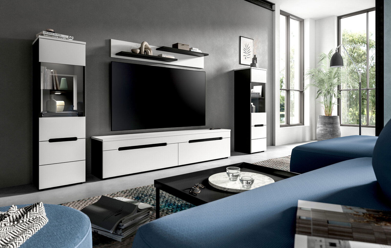 Modernes Wohnzimmer mit weiß-schwarzer TV-Wohnwand (Lowboard, Hängeregal und zwei Vitrinenschränke) vor grauer Wand, frontal aus leicht seitlicher Perspektive aufgenommen.