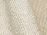 Nahaufnahme eines cremefarbenen Handwebteppichs mit strukturierter Oberfläche, seitliche Perspektive