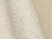 Nahaufnahme eines cremefarbenen Handwebteppichs mit strukturierter Oberfläche, seitliche Perspektive