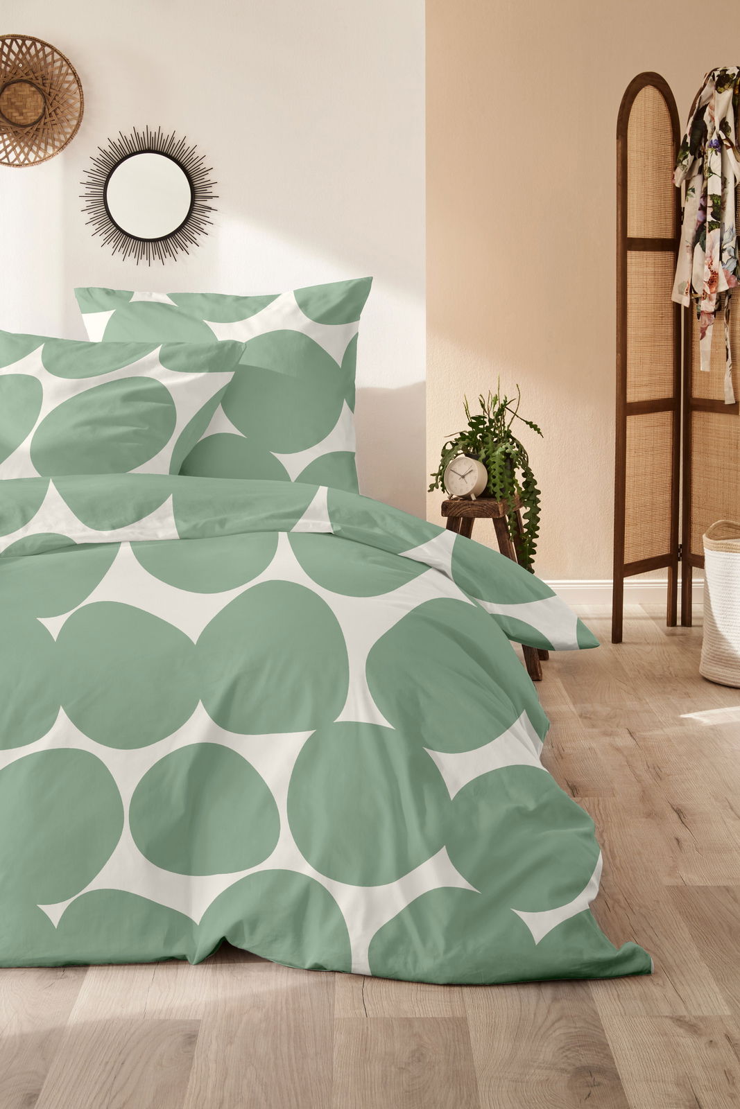 Bettwäsche-Set in Grün und Weiß mit großem Kreismuster, auf einem Bett in einem stilvoll eingerichteten Schlafzimmer, aus der Perspektive von vorne fotografiert.