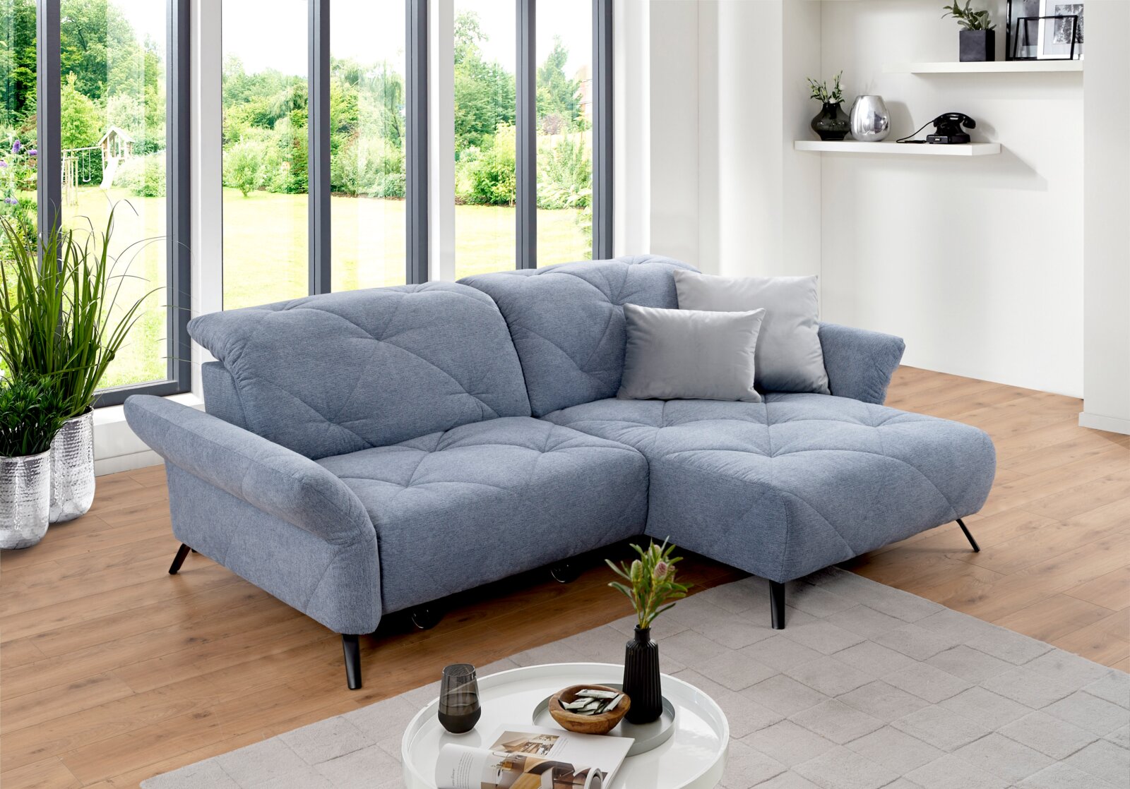 Blauwe longchair-set in een moderne woonkamer met grote ramen en een houten vloer, zijaanzicht