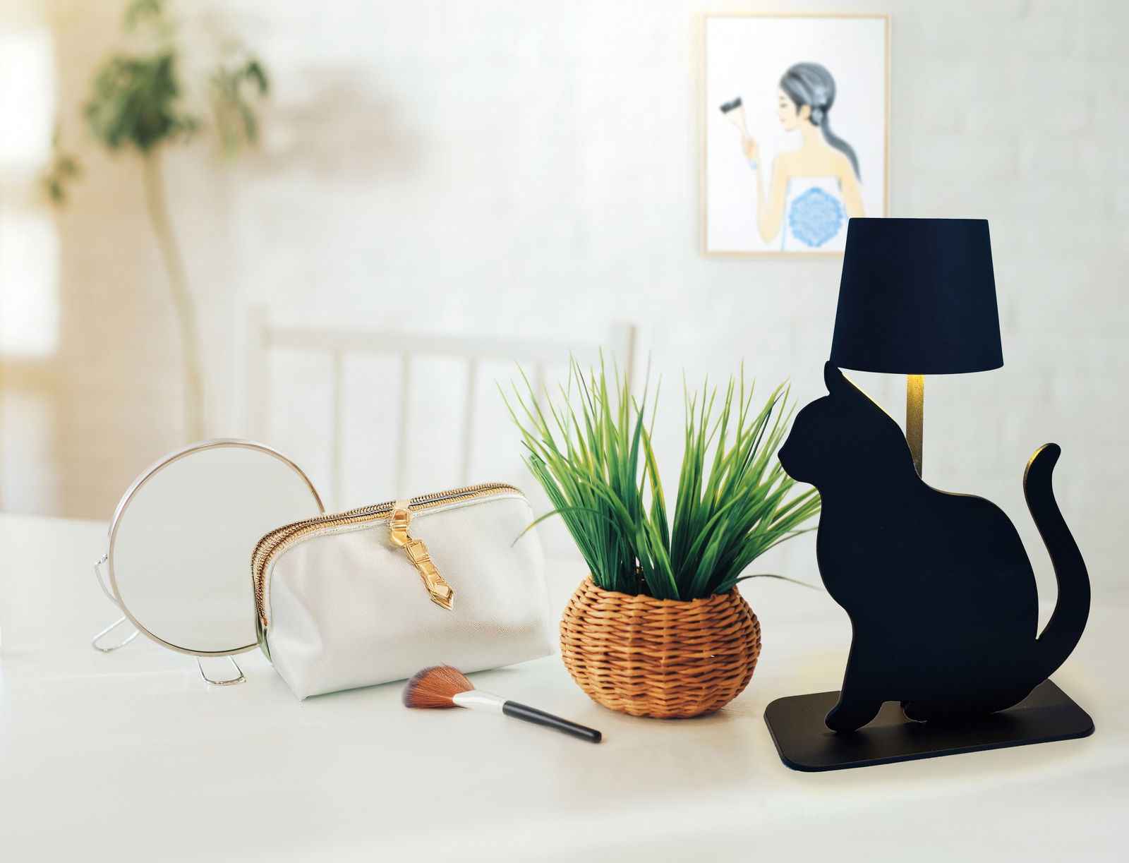 Schwarze Akku-Tischleuchte in Katzenform, seitliche Perspektive, auf einem Tisch neben einem Spiegel, einer Kosmetiktasche und einem Pinsel.