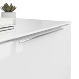 Nahaufnahme einer weißen Nachtkommode mit glänzender Oberfläche, silbernem Griff und Dekorationen wie einem kleinen Pflanzentopf und Büchern auf der Oberseite, aus seitlicher Perspektive.