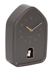 Moderne Wanduhr in Hausform mit braunem Gehäuse und roségoldenen Zeigern, seitliche Perspektive, mit einer kleinen weißen Katzenfigur in einer Öffnung unten.