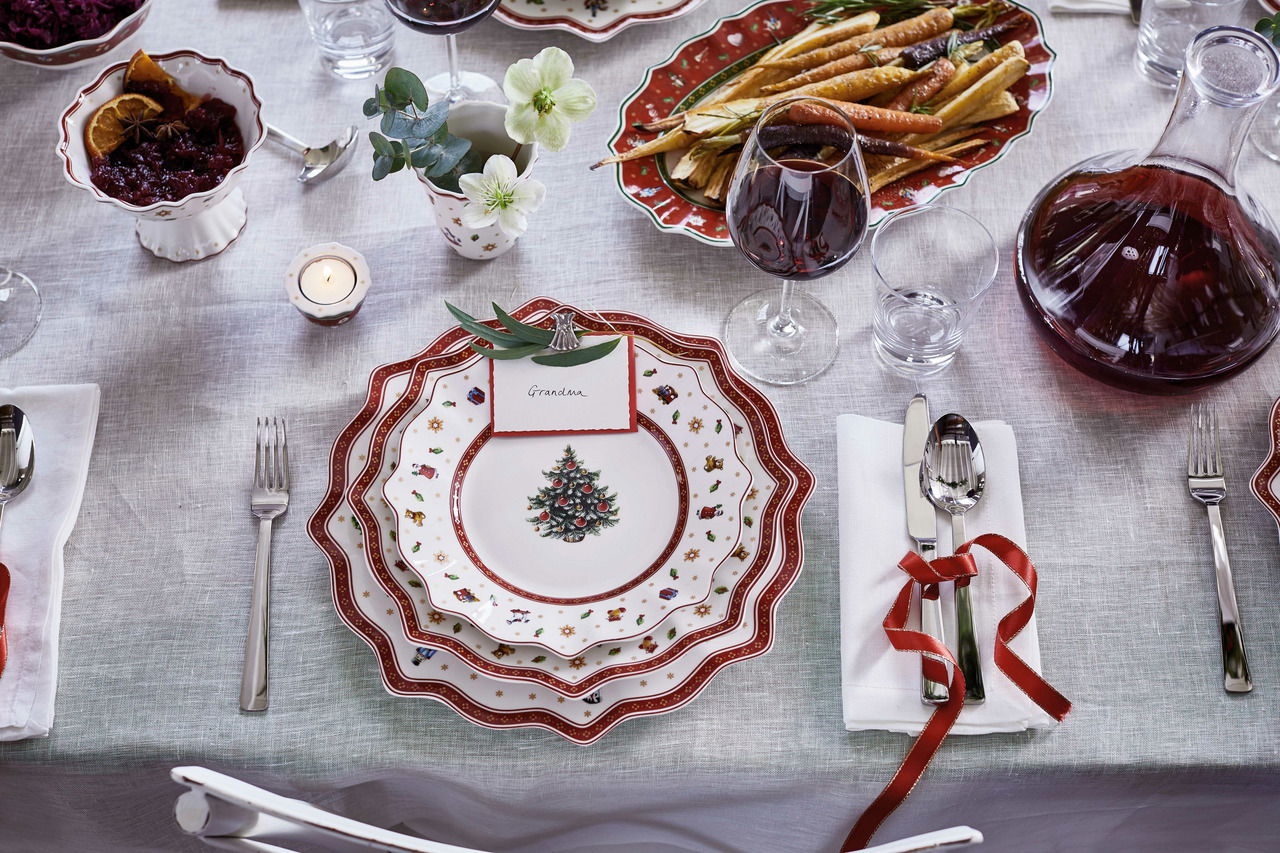 Weihnachtlich gedeckter Tisch mit einem Frühstücksteller in Weiß mit rotem Rand und Weihnachtsbaum-Motiv, von oben fotografiert.