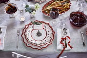 Weihnachtlich gedeckter Tisch mit einem Frühstücksteller in Weiß mit rotem Rand und Weihnachtsbaum-Motiv, von oben fotografiert.
