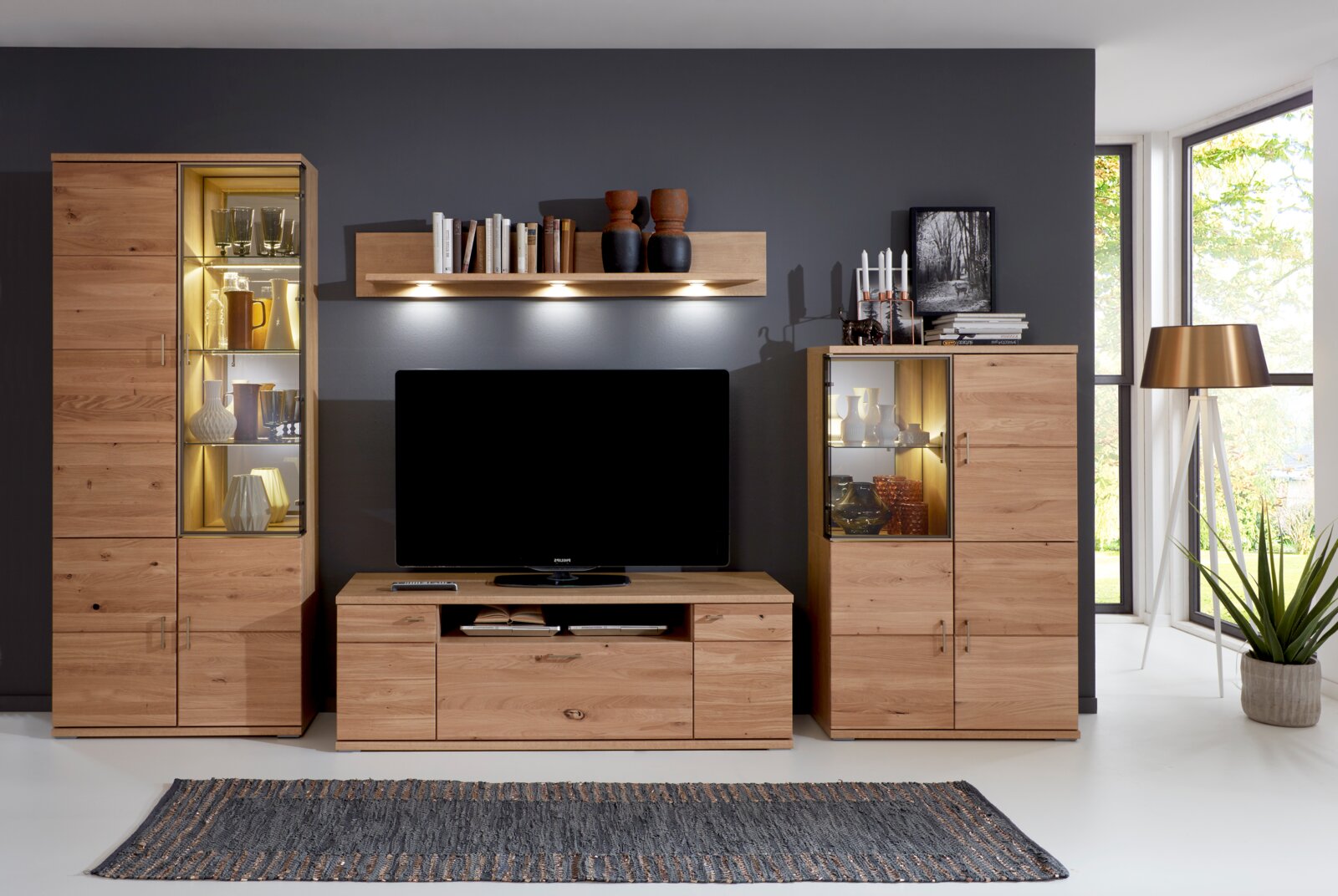 Moderne Wandkombination aus Holz mit Vitrinen und TV-Schrank, frontal betrachtet, in einem stilvoll eingerichteten Wohnzimmer.